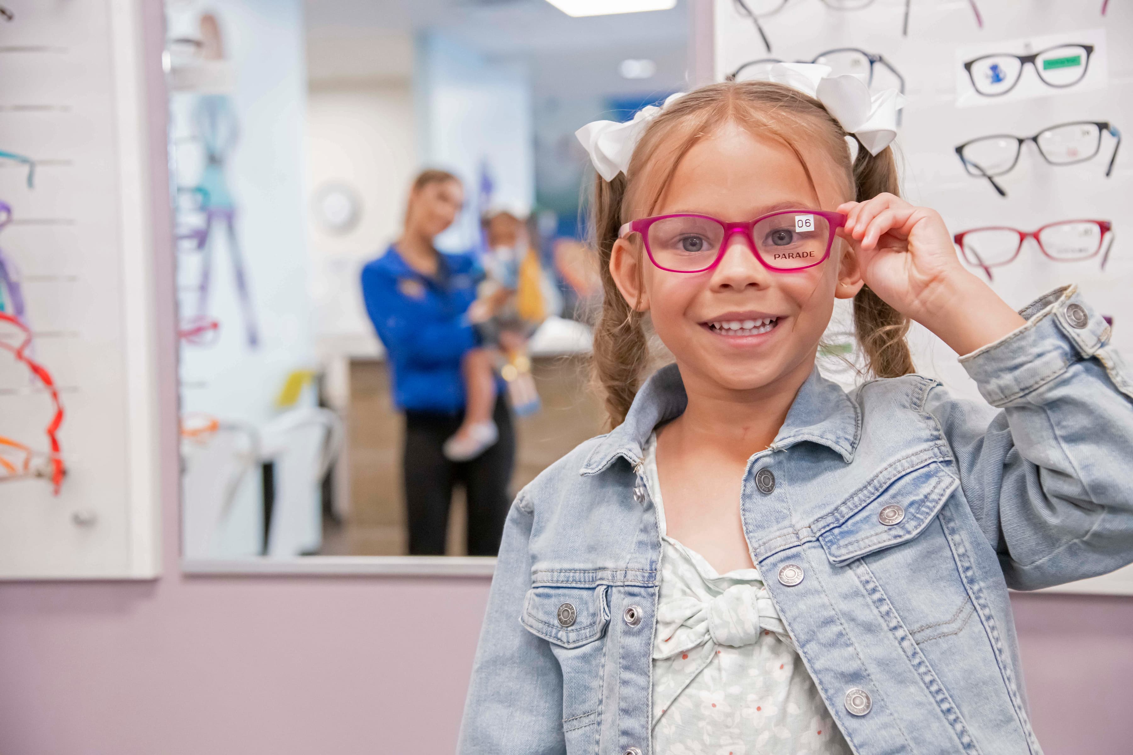 Young girl trying on pink glasses at a children's optometrist office