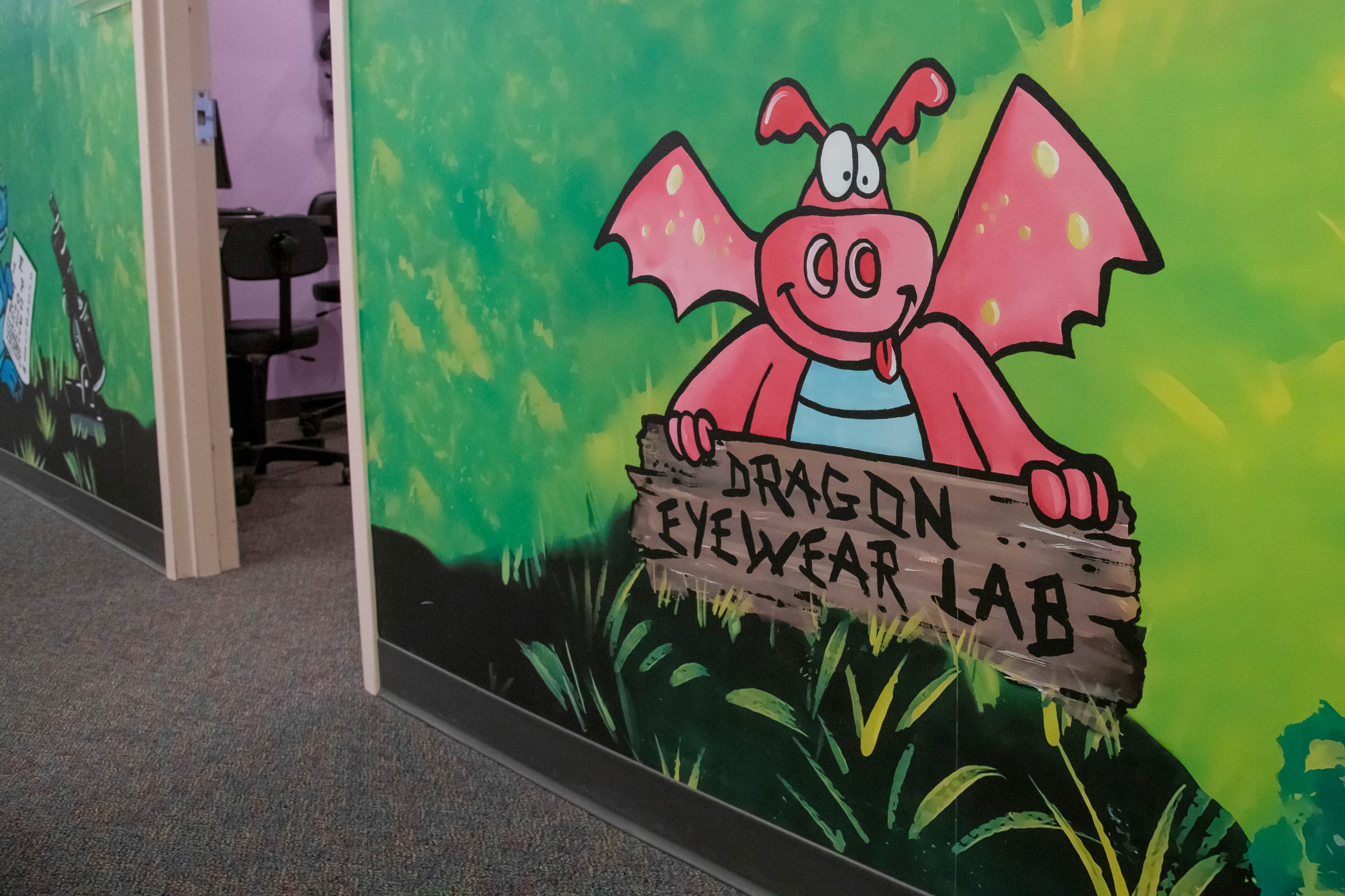 pink cartoon dragon holding a sign that says dragon eyewear lab