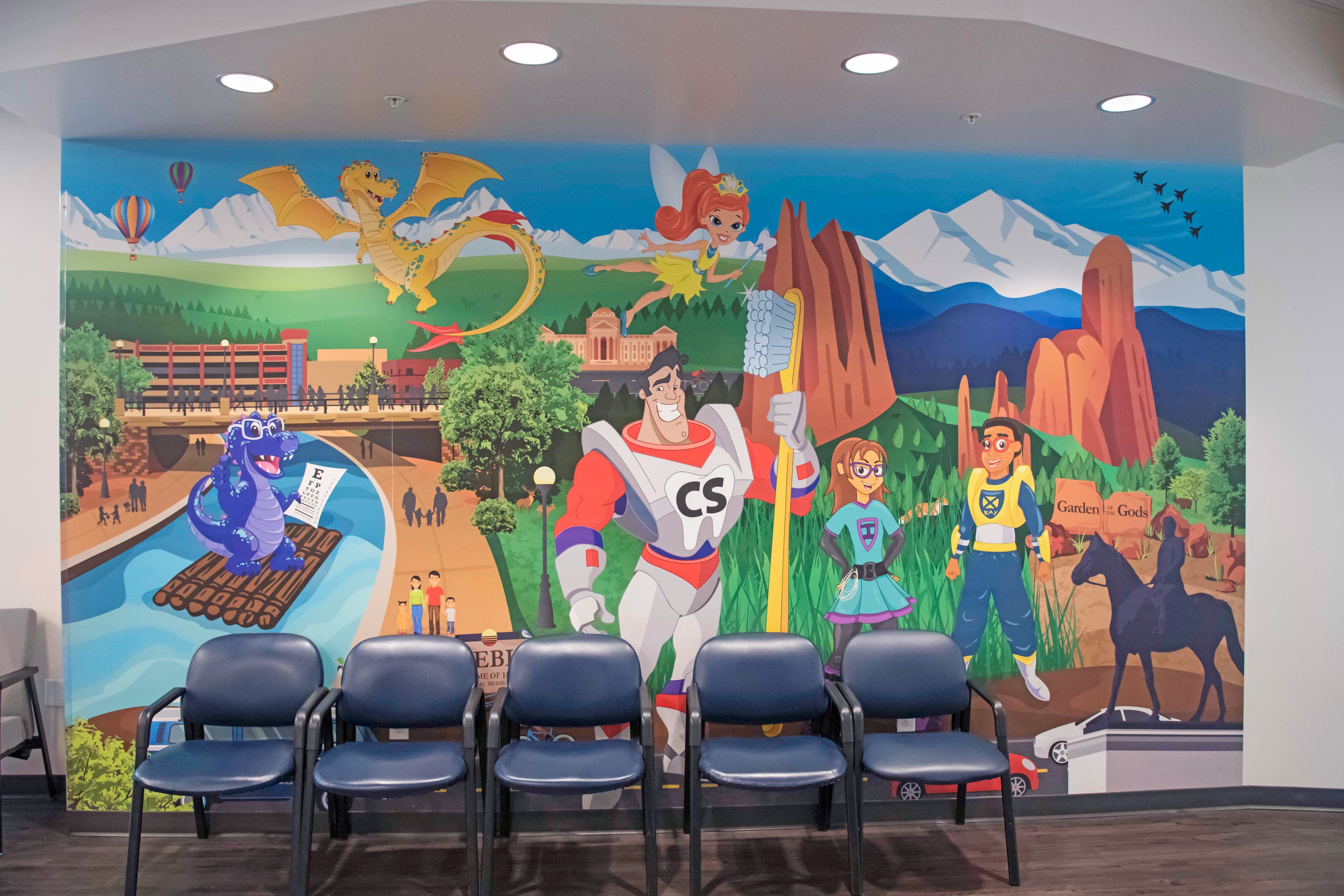 sitting area with blue chairs and large colorful graphic in the background with illustrated characters including a dragon and dinosaur