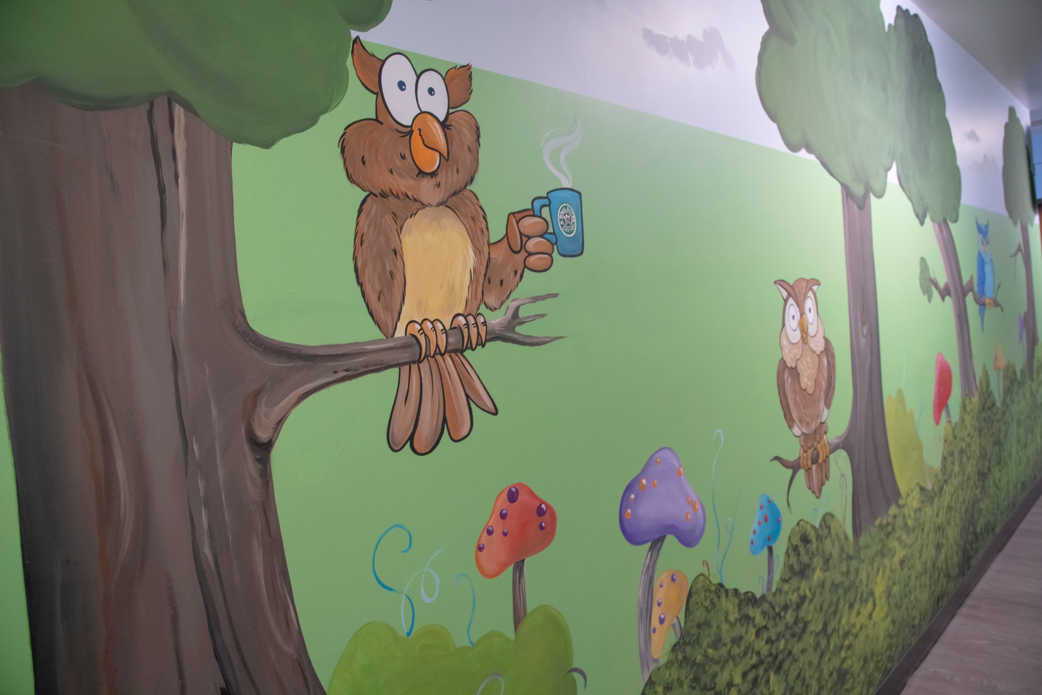 graphic of an owl sitting on a tree limb holding a cup