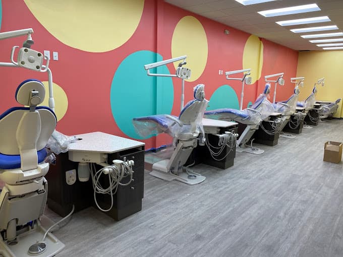 Dental and orthodontics exam room with five chairs with multicolor polka dots on the wall