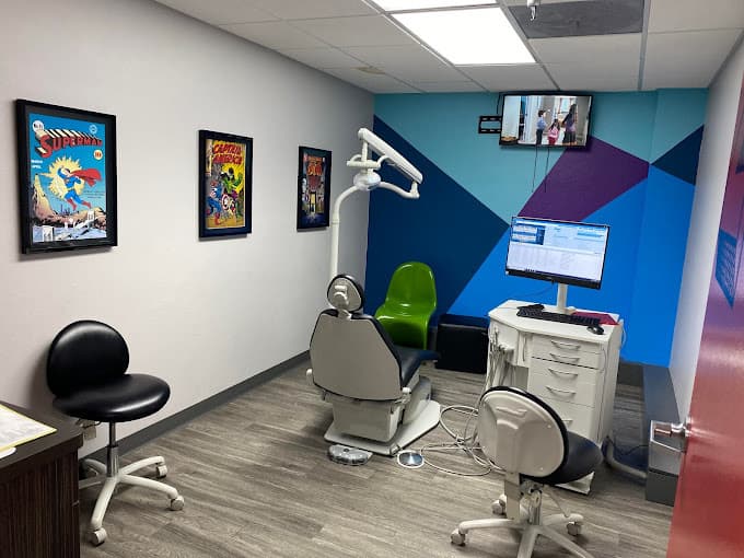 Dental and orthodontics exam room with three pictures on the wall and multicolored mural with one dental chair