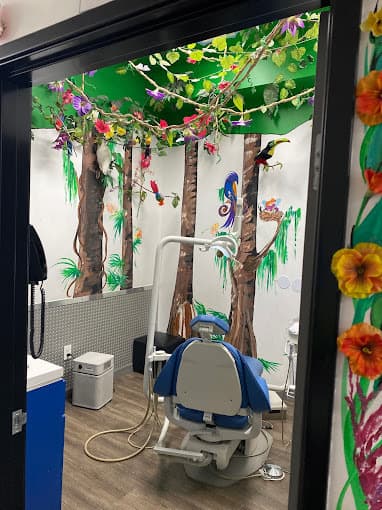 Dental and orthodontics exam room with one chair and a colorful forest scene painted on the wall