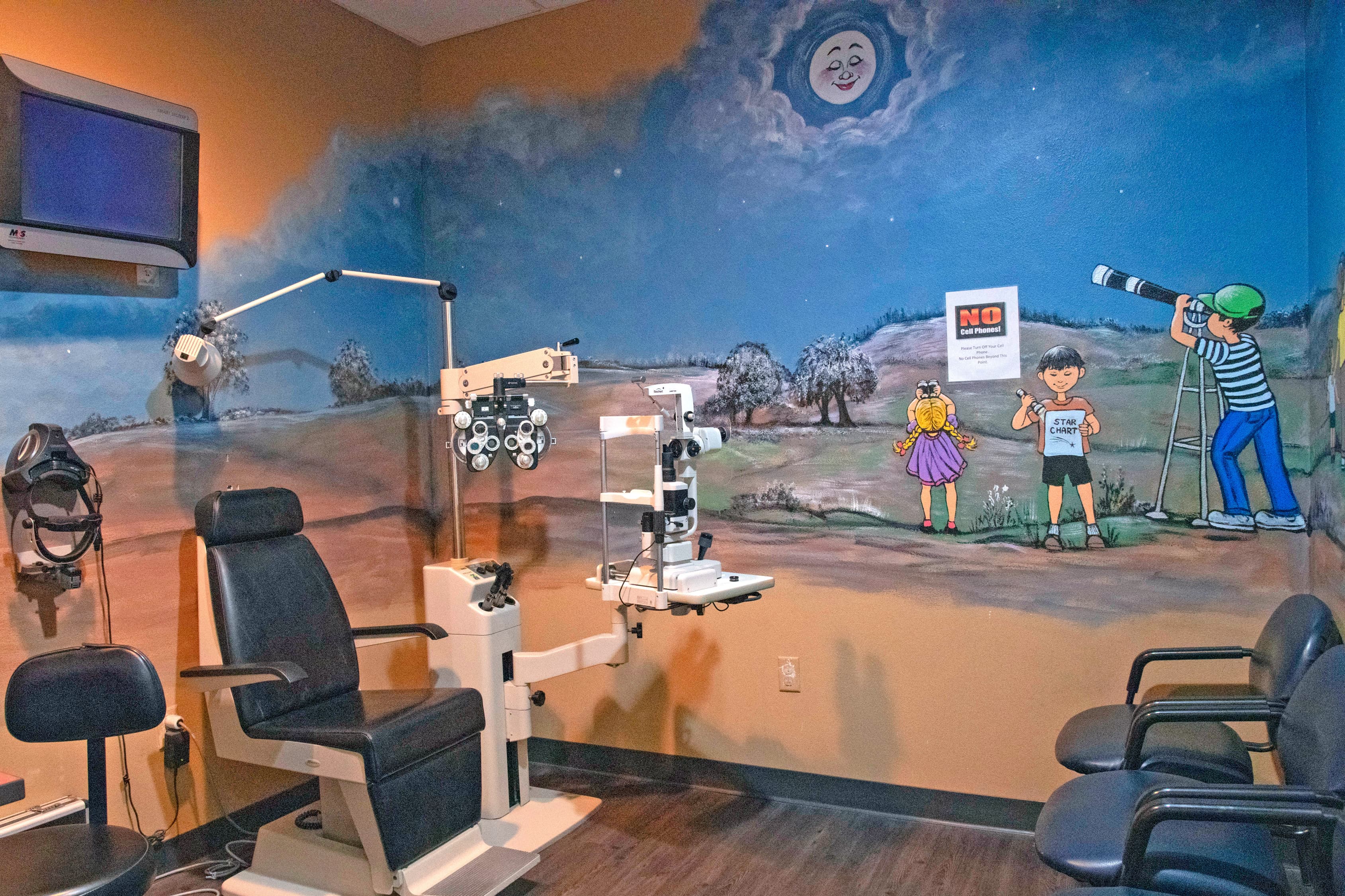 pediatric vision exam room with colorful wall mural and one optometrist chair