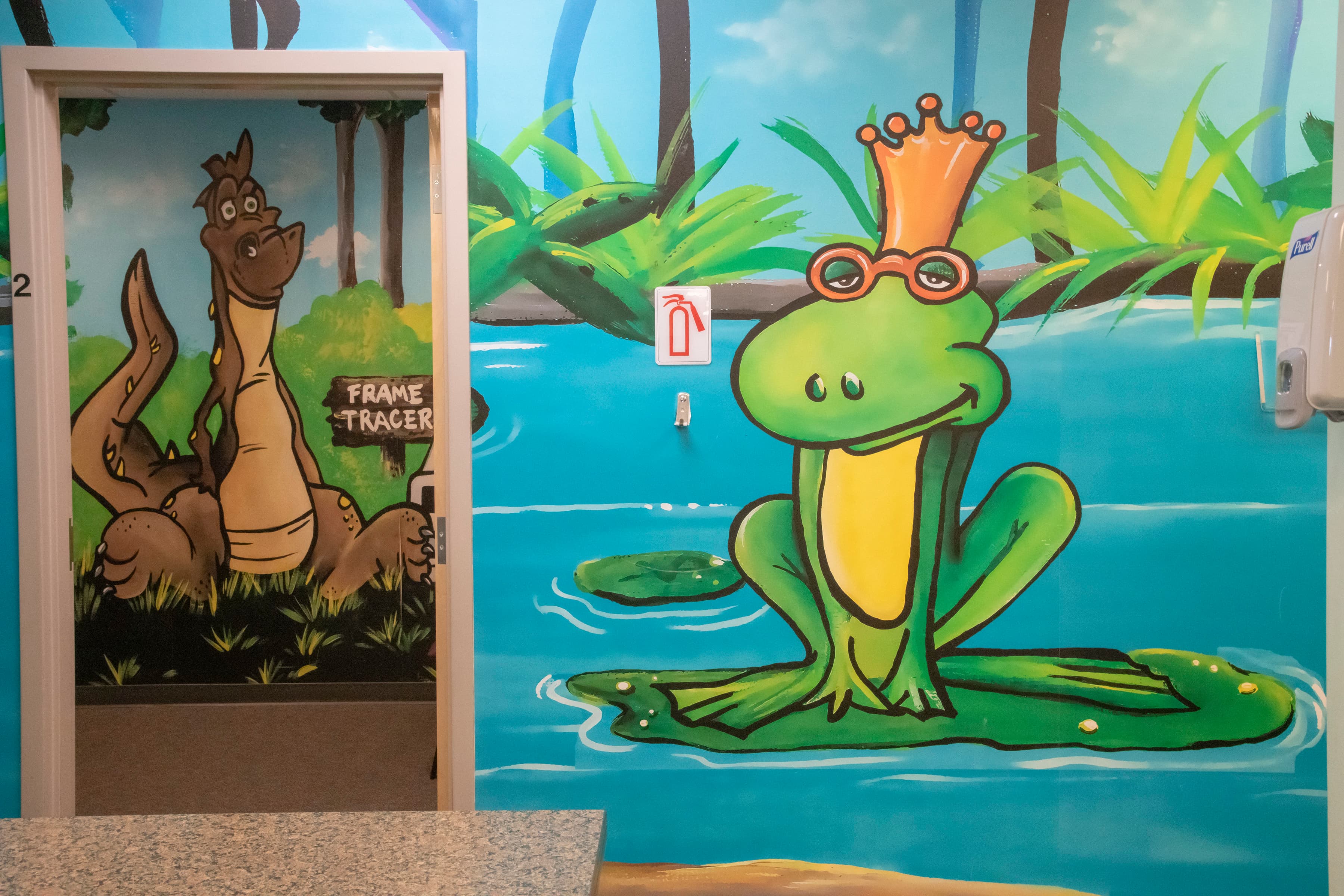 a frog wearing glasses and a crown and a dinosaur painting on the wall in the background