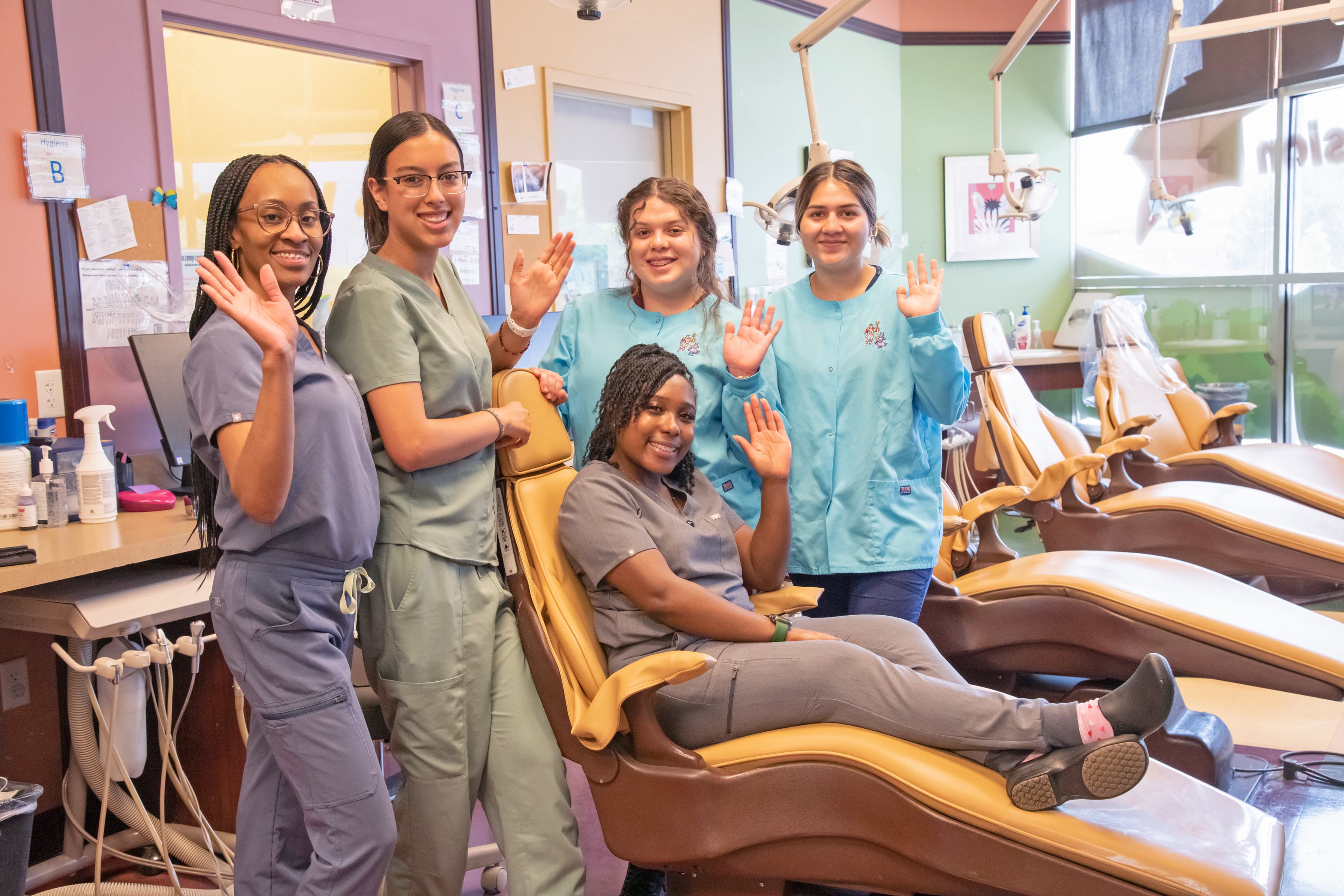 Pediatric dental care staff at Colorado Springs location on north academy. Staff is wearingcolorful scrubs and one person is sitting in a dental chair.